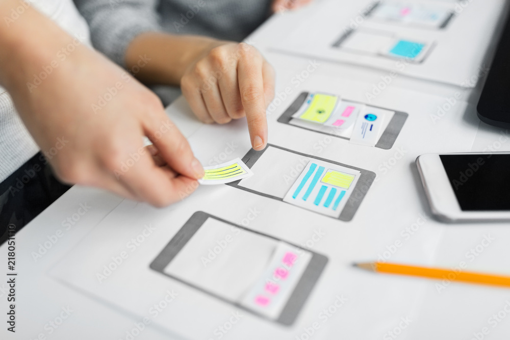 app design, technology and business concept - web designers or developers working on user interface wireframe layout at office app design, technology and business concept - web designers or developers working on user interface wireframe layout at office