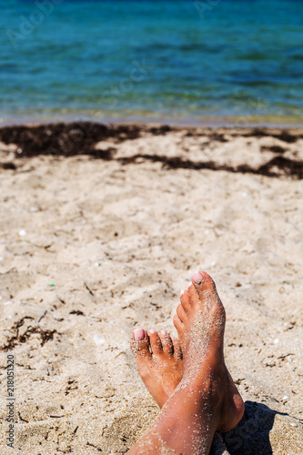 Beach travel concept. Legs on Tropical Sand Beach.