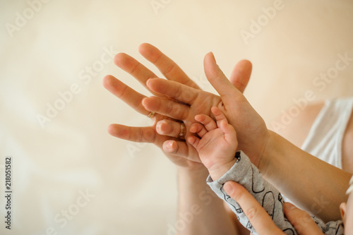 Close up of parents and kid join hands on the light background