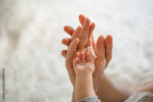 Close up of parents and baby join hands on the light background