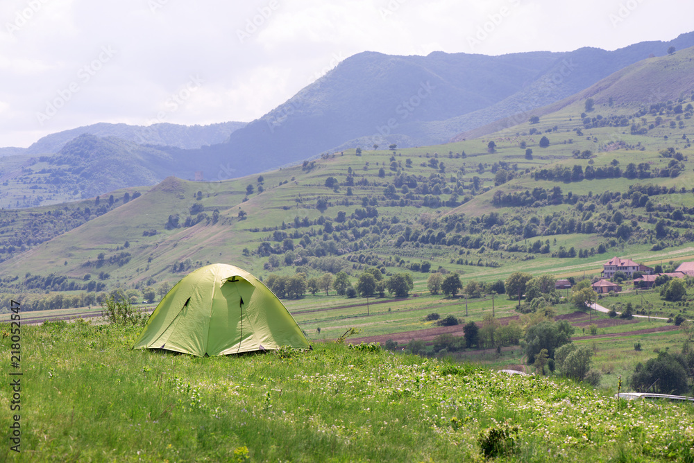 Tent is built in meadow. Beautiful, fresh morning in mountain landscape next to medieval village. Concept of freedom, camping and travelling around the world. Picnic in nature  