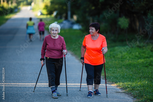 An elderly woman is engaged in Nordic walking with her adult daughter.