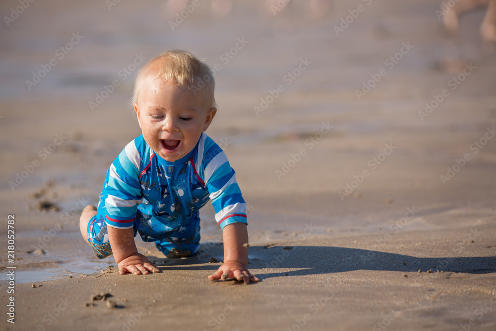 Little baby boy, playing on the ocean beach with toys Little baby boy, playing on the ocean beach with toys