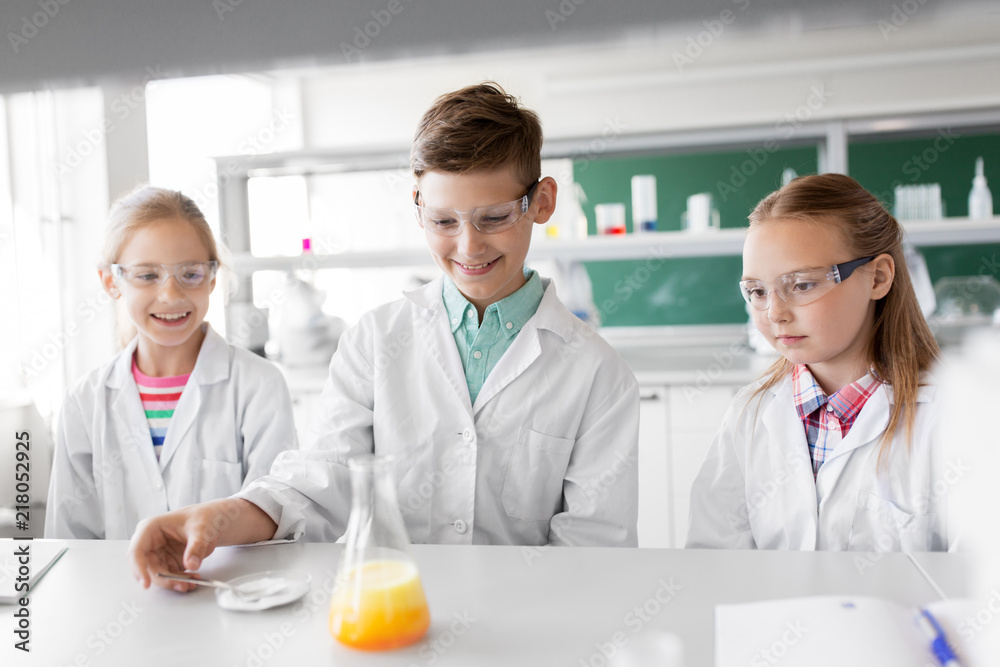 Fototapeta premium education, science, chemistry and children concept - kids or students with test tube making experiment at school laboratory