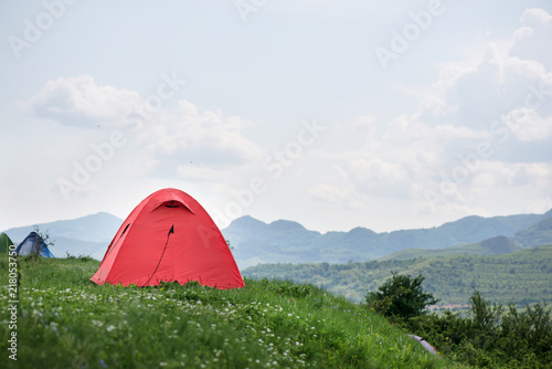 Tent is built in meadow. Beautiful  fresh morning in mountain landscape next to medieval village. Concept of freedom  camping and travelling around the world. Picnic in nature  