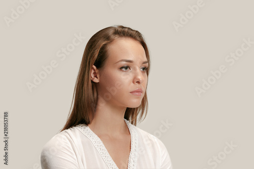 Serious business woman isolated on gray studio background. Beautiful, young face. Female front portrait. Human emotions, facial expression concept
