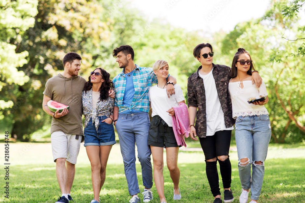 friendship and leisure concept - group of happy friends with picnic blanket and watermelon walking at summer park friendship and leisure concept - group of happy friends with picnic blanket and watermelon walking at summer park
