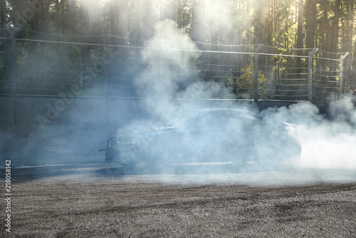 Drift car warming up the tires before  start  waiting for race to begin. Blue and purple smoke all around.    