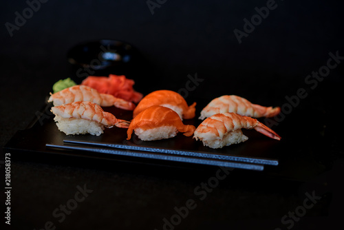 Sashimi sushi set on a black wooden board for sushi on black background. Close up of sashimi sushi with prawns. Traditional japanese food. Sushi menu. Delicious dinner in the restoran. Selective focus
