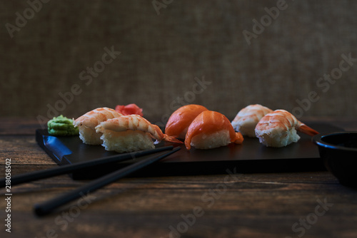 Sushi roll with salmon, eel, calf caviar and cheese. Sushi menu. Japanese food. Sushi on dark background. Japanese cuisine, sushi set: sushi and sushi rolls on wooden plate, selective focus.