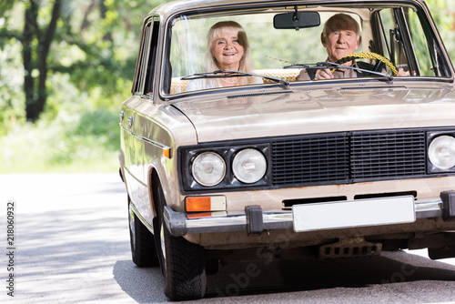 senior couple driving beige vintage car