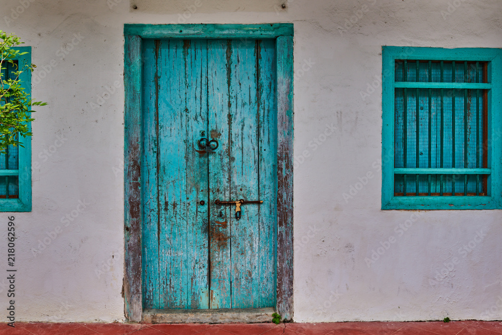 Old house wall with wooden door and window.