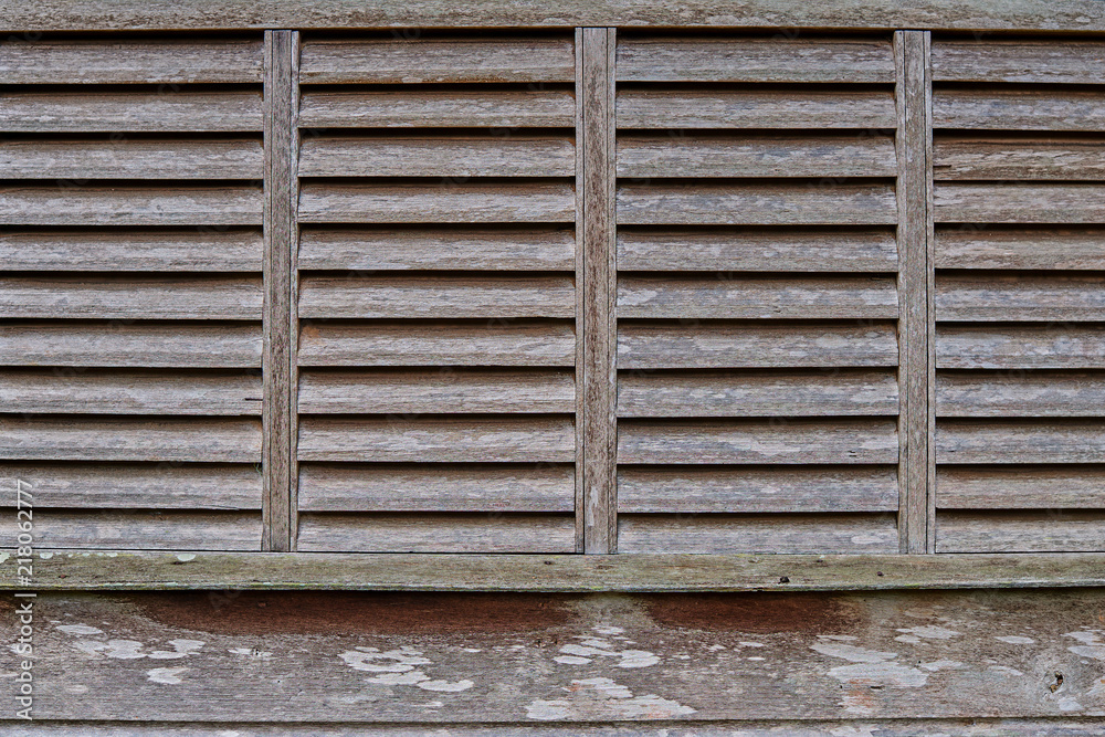 Old wooden blinds on the windows. The textured corrugated shutter or wooden sun protection blinds for a background and for wallpaper. Old wooden blinds on the windows. The textured corrugated shutter or wooden sun protection blinds for a background and for wallpaper.