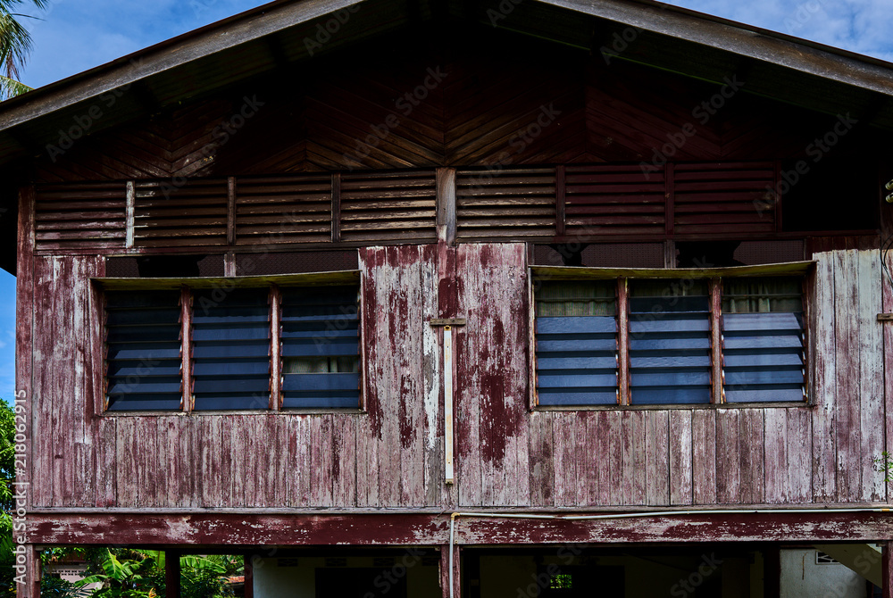 Weathered old house and windows with peeling paint and rotten wooden plank