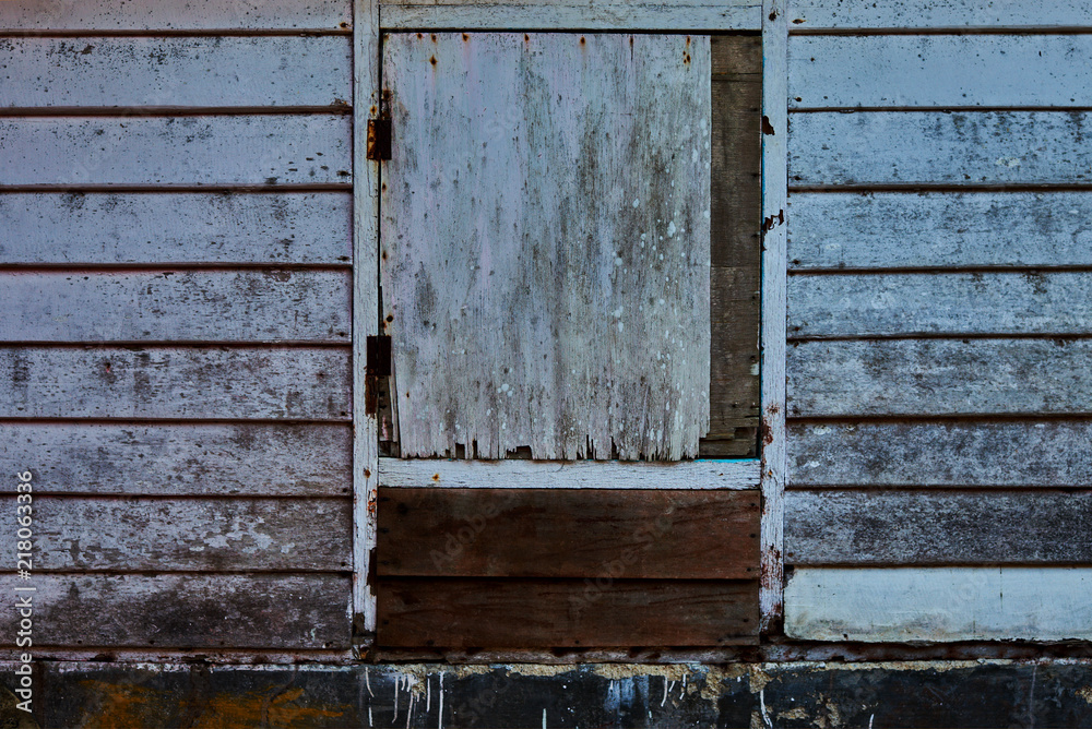 Window with  broken wooden shutters on the wooden wall. Wooden wall paneling with texture. Old  wood slats shabby. Grunge weathered surface. Natural background..