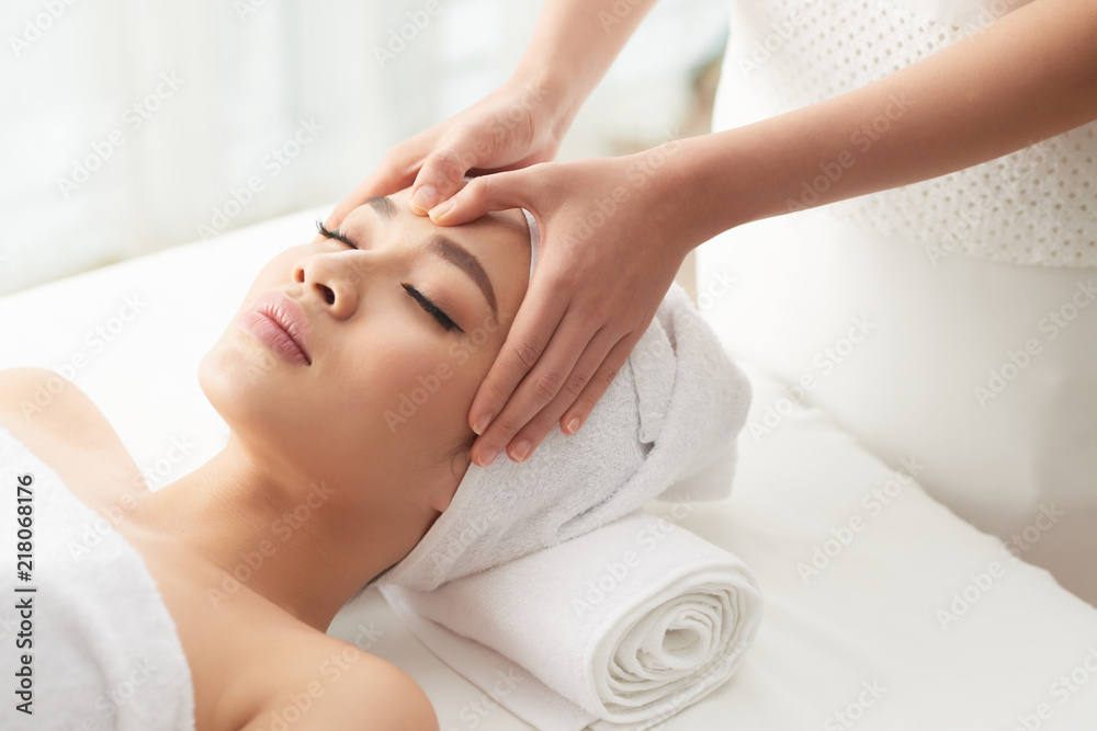 From above shot of unrecognizable woman massaging forehead of beautiful woman while working in spa salon From above shot of unrecognizable woman massaging forehead of beautiful woman while working in spa salon