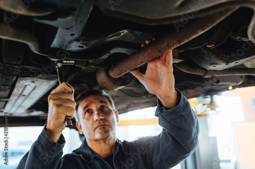 Foto Mechanic working under a lifted car