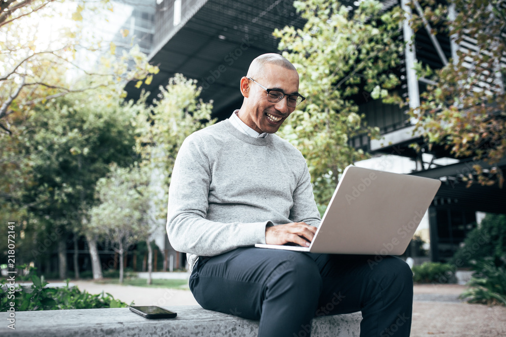 Businessman working on laptop computer sitting outdoors Businessman working on laptop computer sitting outdoors