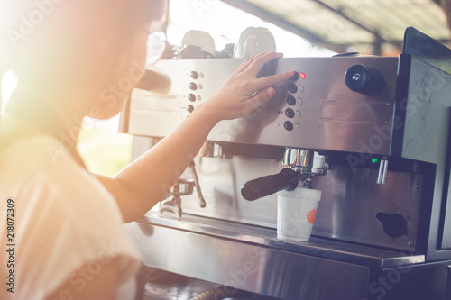 A woman who works in a coffee shop. She was making coffee with coffee machine. photo