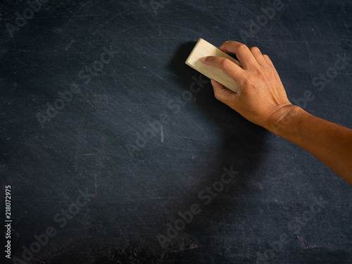 Hand holding brush eraser and blackboard..