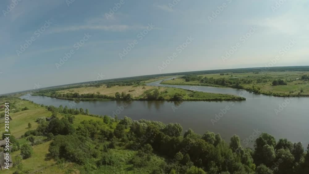 Quadrocopter, flies over the river enveloping a small island. There are many trees along the river. Summer sunny day. Video shooting from a bird's-eye view. Forest, river, in the distance can be seen Quadrocopter, flies over the river enveloping a small island. There are many trees along the river. Summer sunny day. Video shooting from a bird's-eye view. Forest, river, in the distance can be seen
