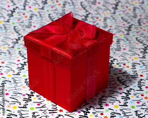 Bright red shiny gift box with bow on white birthday background
