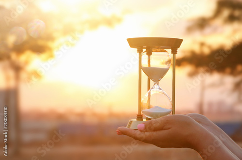Young woman holding Hourglass during sunset. vintage style.