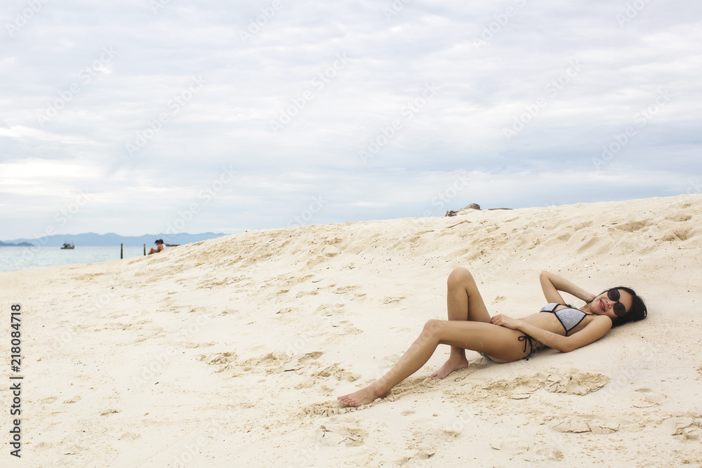 Young Asian woman in bikini laying on sandy beach, sexy woman enjoy at the beach Young Asian woman in bikini laying on sandy beach, sexy woman enjoy at the beach