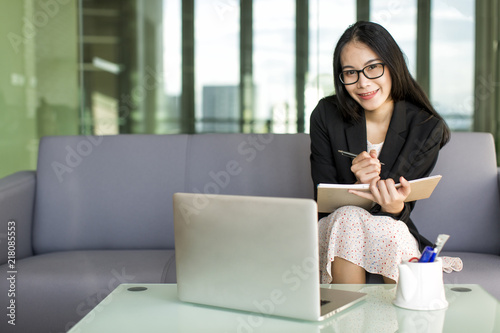 Young Asian businesswoman in suit and sweet dress working with laptop at office, professional working proficiency with smile and happy.