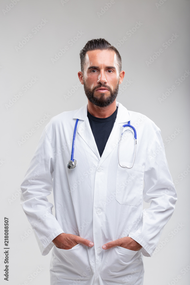 Serious bearded doctor with hands in pockets Serious bearded doctor with hands in pockets