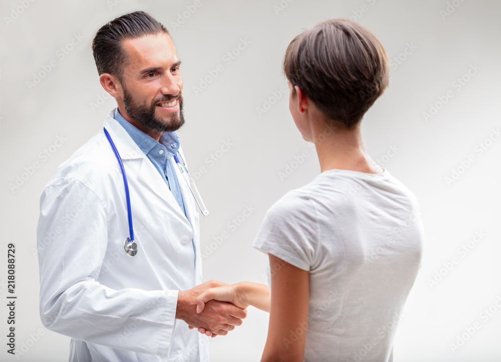 Smiling male doctor shaking hands with a patient Smiling male doctor shaking hands with a patient