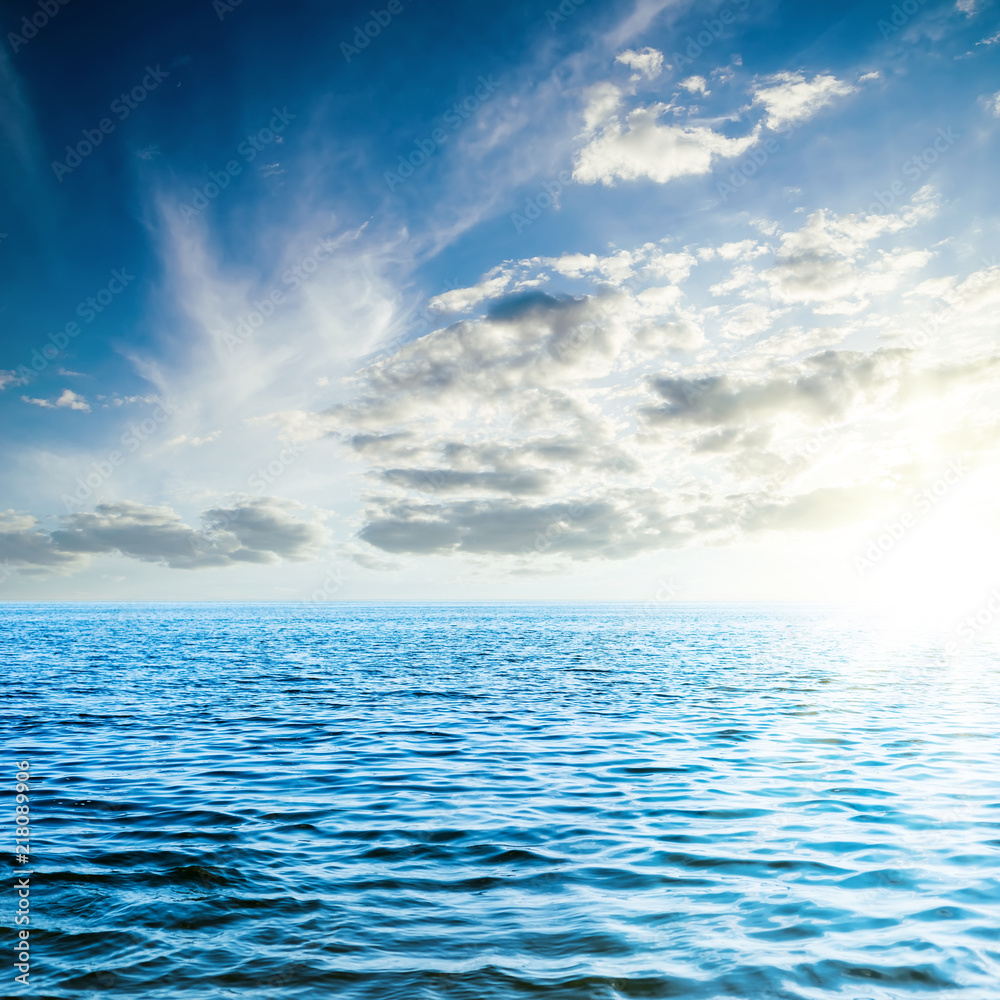 Fototapeta premium sunset in low dark clouds over blue sea