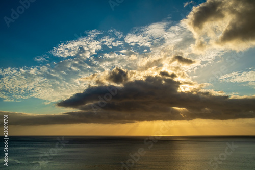Sunset behind some clouds over the sea with orange and blue sky © Sário Nunes