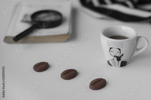 Minimalist composition. Life style. A cup of coffee, cookies, a notebook with a magnifier on a white background. photo