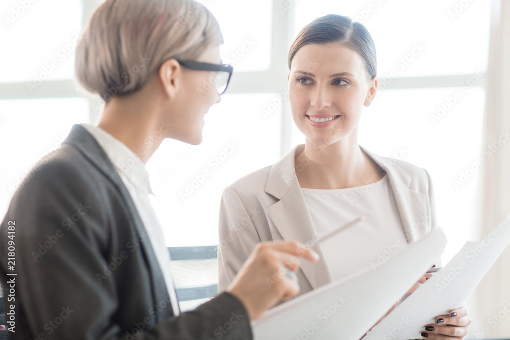 Obraz premium Adult trendy women sitting in bright daylight with papers and having friendly business meeting 