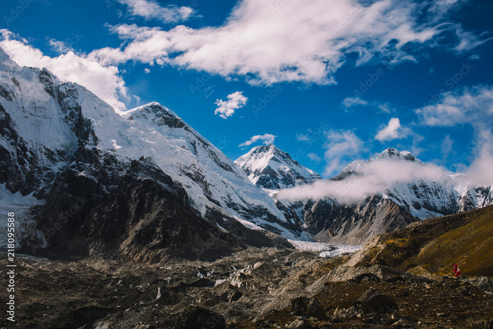 High mountains with snowy peaks in clouds at bright sunny day in Nepal. Colorful landscape with beautiful rocks and dramatic cloudy sky. Nature background. Amazing mountains. Way to Everest base camp.