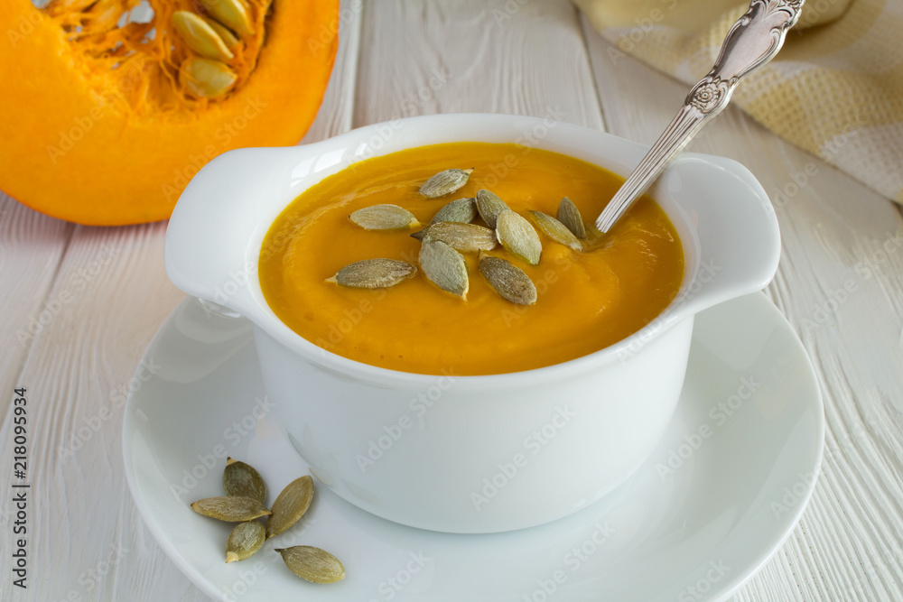 Soup with pumpkin in the plate on the white wooden background.Closeup. Soup with pumpkin in the plate on the white wooden background.Closeup.