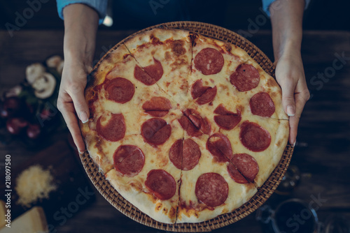 Chef offering pizza in hotel or restaurant. Italian pizza with mushrooms and salami. Italian restaurant. Delicious fresh pizza with appetizing crust, close up. Italian food, pizzeria concept.