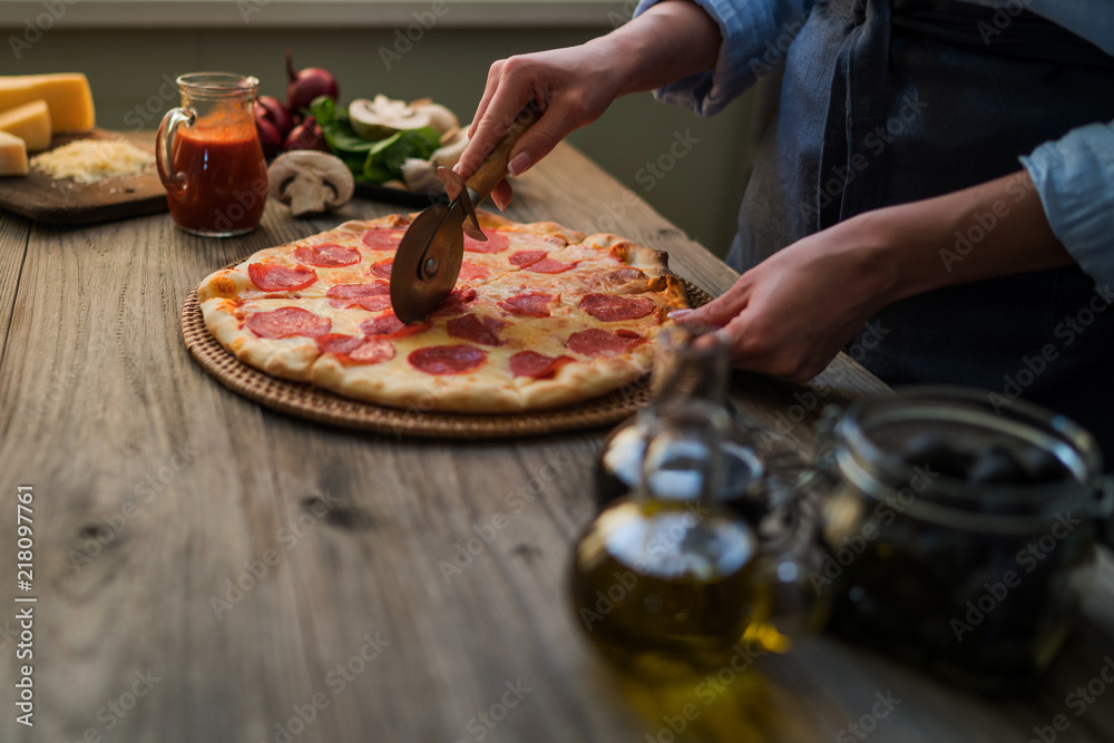 Cook's hands making homemade pizza on the table. Pizza with ingredients. Tomatoes, garlic, parsley, pepper, parmesan cheese on dark wooden background. Food, family and people concept.