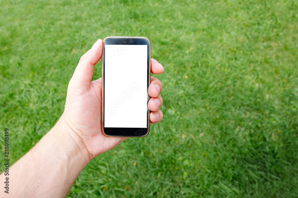 Phone in hand men in the background lush green grass. Mockup for design