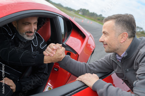 Фотография sportscar pilot shaking hands with his engineer on race track