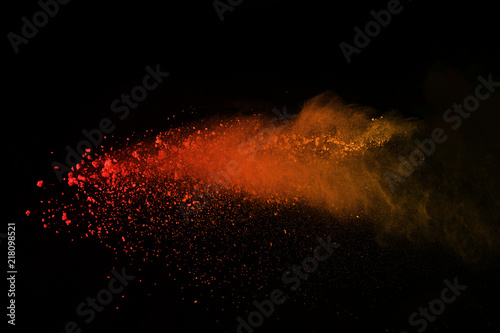 Explosion of colored powder isolated on black background. Power or clouds splatted. Freez motion of orange dust exploding.