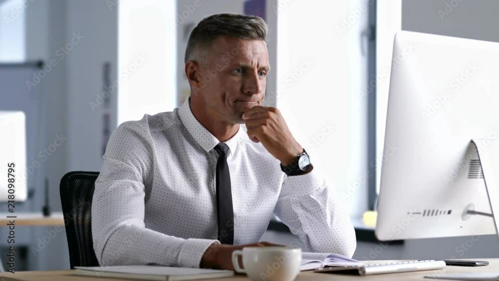 Happy handsome businessworker using computer and talking about planning with his colleague in office Happy handsome businessworker using computer and talking about planning with his colleague in office