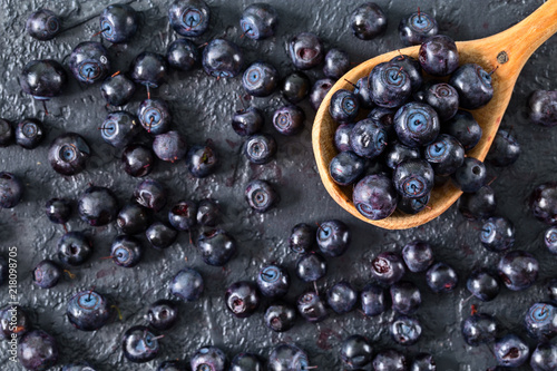 Fresh blueberries in a wooden spoon on stone table