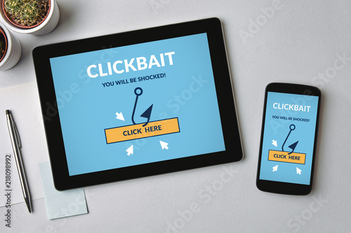 Clickbait concept on tablet and smartphone screen over gray table. All screen content is designed by me. Flat lay