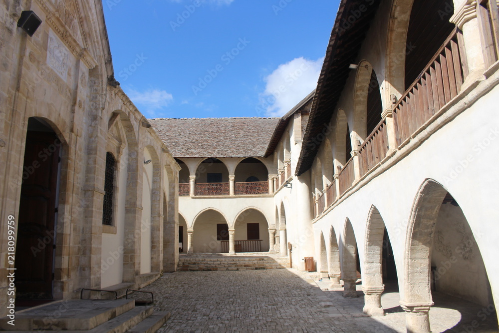 Courtyard of Timios Stavros Monastery, located near the mountain village Omodos, surrounded by two-story buildings with arcades.