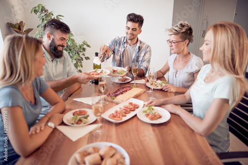 Smiling friends having dinner and drinking wine at home