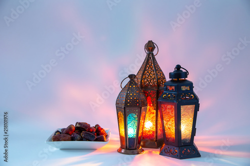 Arabic, Moroccan lanterns and dates in low light, on white background with colors reflections and copy space. Eid and Ramadan concept.