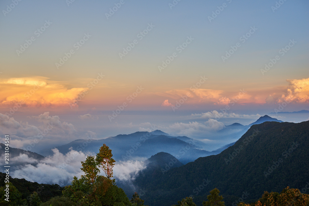 Mountain landscape at sunrise. View from the mountain peak on rocks, low clouds, blue sky and clouds at sunrise. Colorful nature background. Adventure. Travel.  Beautiful scenery.