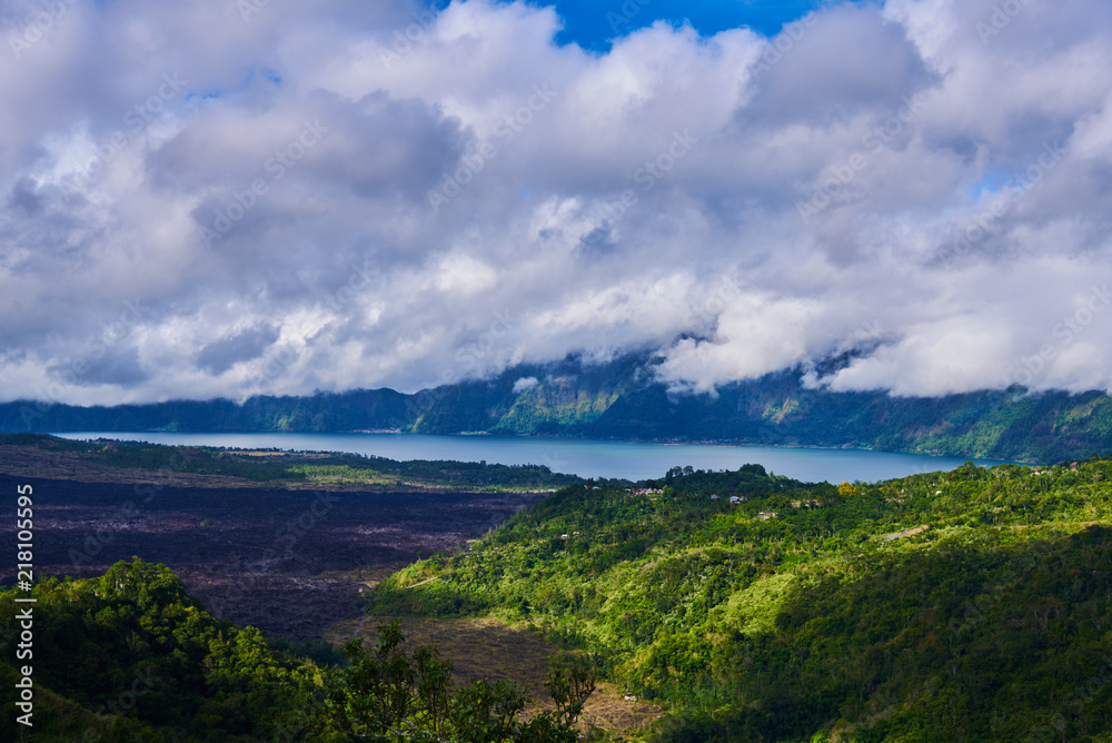 The Batur lake and volcano are in the central mountains in Bali, Indonesia. Beautiful natural landscape in the summer time. Mountains under clouds in the sun day. Natural background. Landscape.
